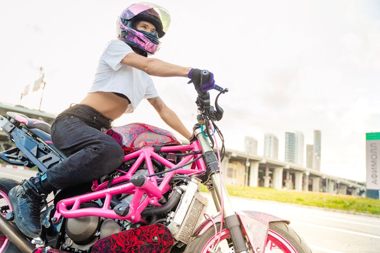 A Woman Wearing A White Crop Top Riding A Motorcycle