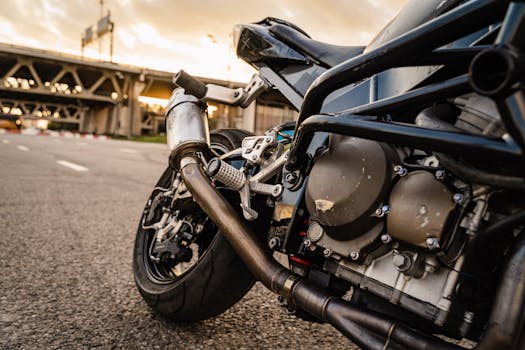 Detailed view of a motorcycle engine parked under a bridge during sunset with asphalt background.