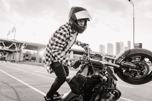 Free Male motorcyclist performs a thrilling stunt on a city street, showcasing skill and adrenaline. Stock Photo