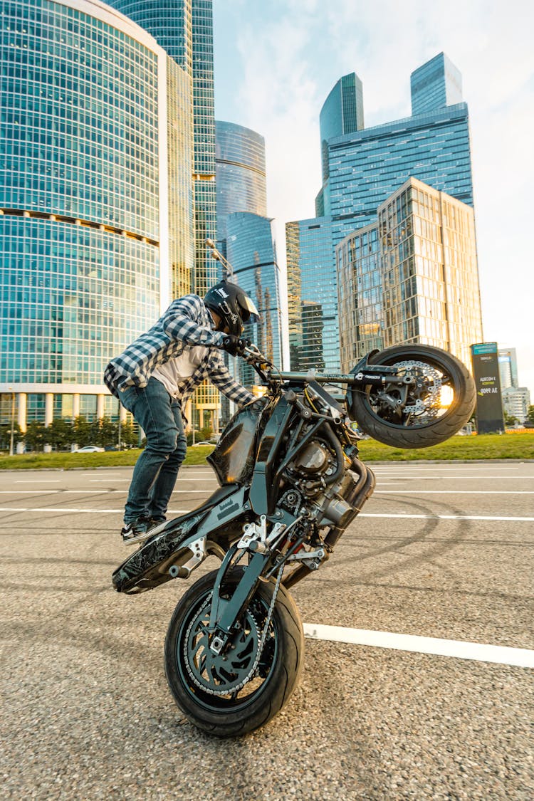 Man In Plaid Shirt Riding On A Motorcycle Doing A Stunt