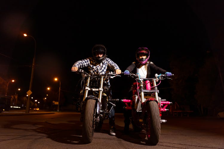 A Man And A Woman Riding Their Motorcycles At Night