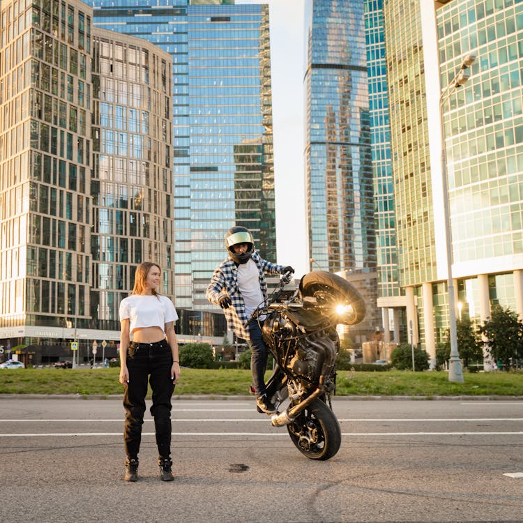 A Person Doing A Motorcycle Stunt Beside A Woman