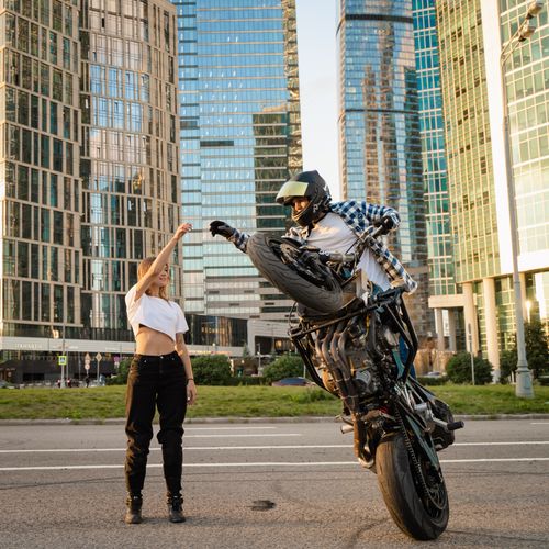Free Motorcyclist performing an impressive stunt with a cheering friend in a modern city. Stock Photo