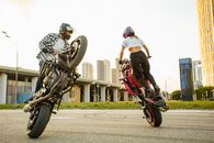Man and Woman Riding on Motorbikes Doing Stunt