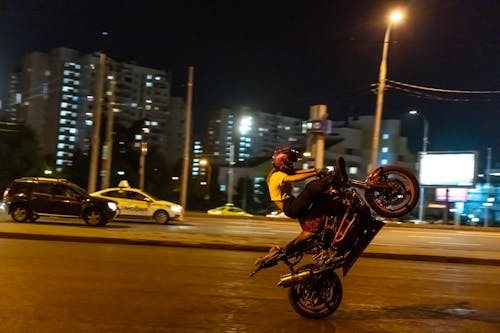 Woman in Yellow Shirt Riding Black Motorcycle on Road during Night Time