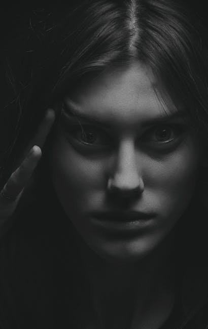 Close-up monochrome portrait of a woman with intense gaze in a dramatic setting.