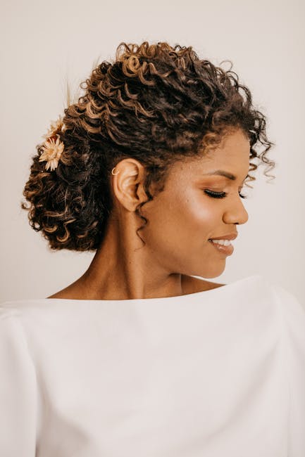 Beautiful portrait of an adult woman with curly hair, a flower accessory, and eyes closed in peaceful expression.