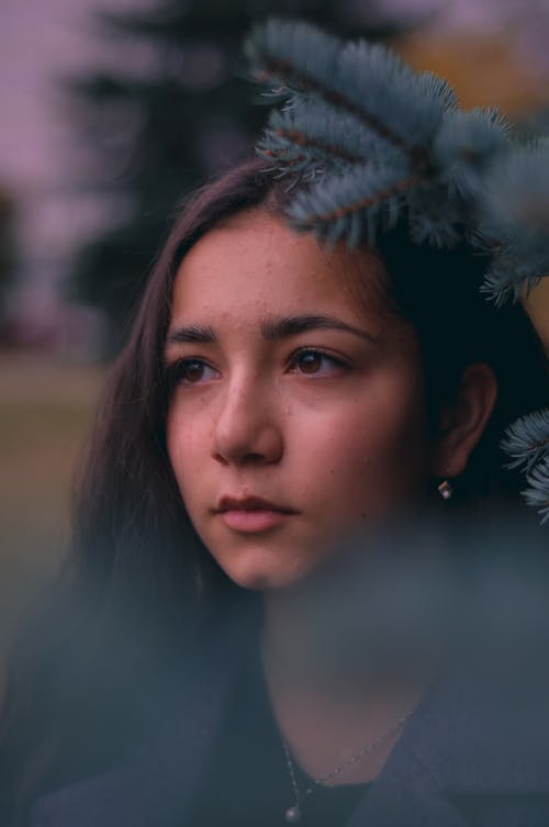 Young Woman Standing next to a Spruce Tree 