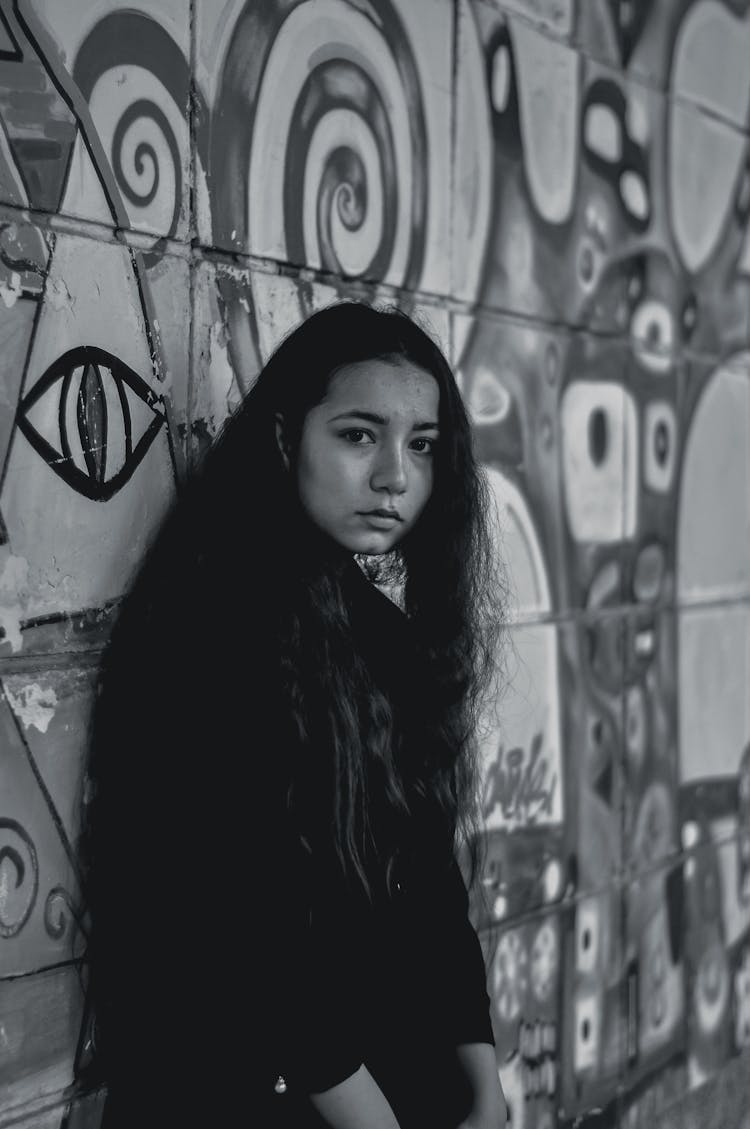 Young Woman In Black Jacket Standing Beside Wall With Painting