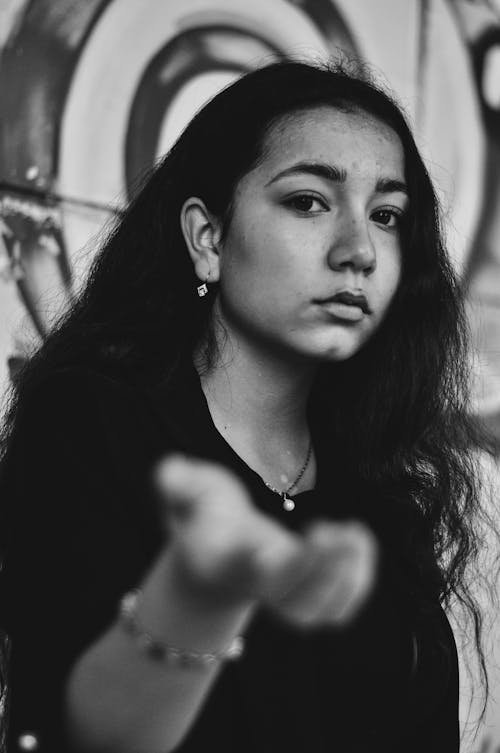 Grayscale Photo of Woman in Black Shirt Reaching Out Her Hand