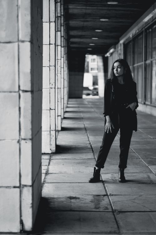 Free Black and white photo of a woman in casual clothing posing in an urban corridor. Stock Photo