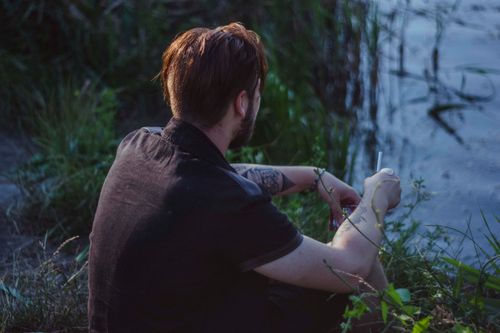 Free A man sitting by the river at dusk, enjoying a peaceful moment outdoors. Stock Photo