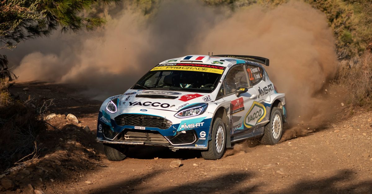 Rally car speeds through a dusty countryside track, showcasing agility and power.