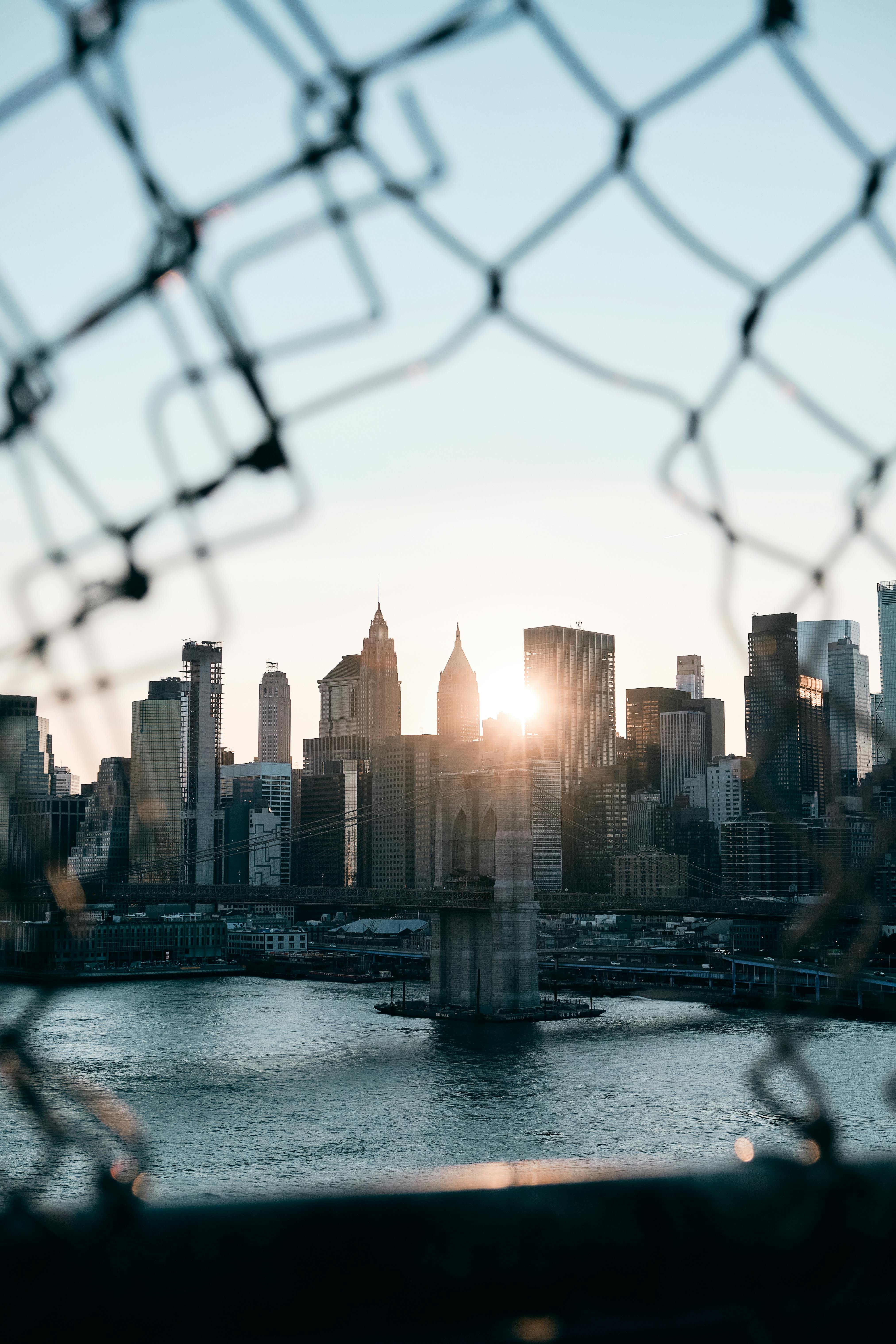 view through hole in fence on bridge on skyscrapers in city