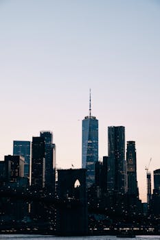 Iconic New York City skyline featuring skyscrapers and Brooklyn Bridge during twilight.