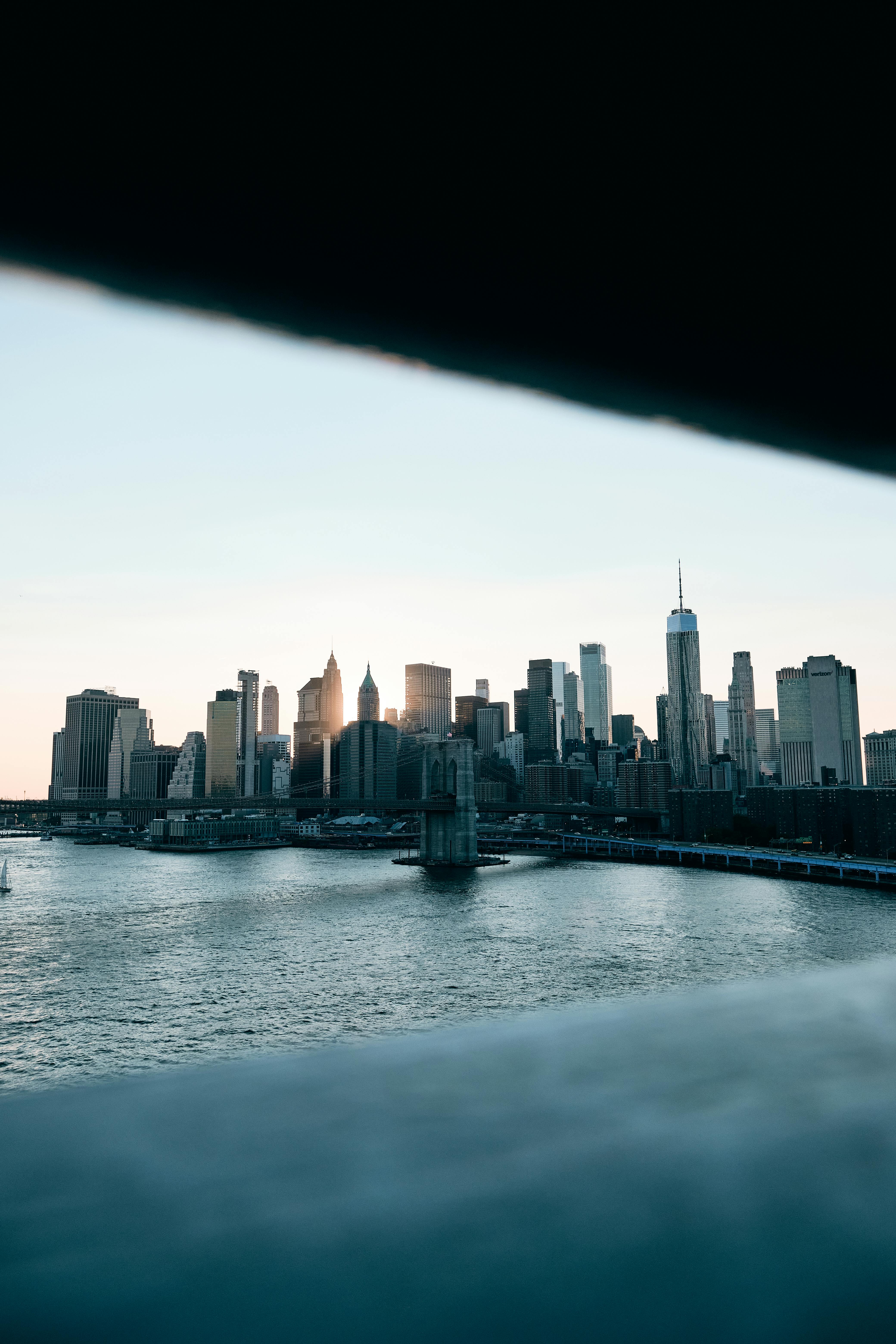 Striking view of New York City skyline with prominent skyscrapers and river at sunset.
