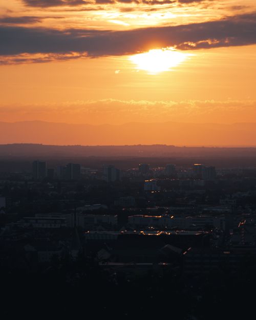 Free Silhouette of city buildings against a dramatic sunset sky, creating a serene cityscape view. Stock Photo