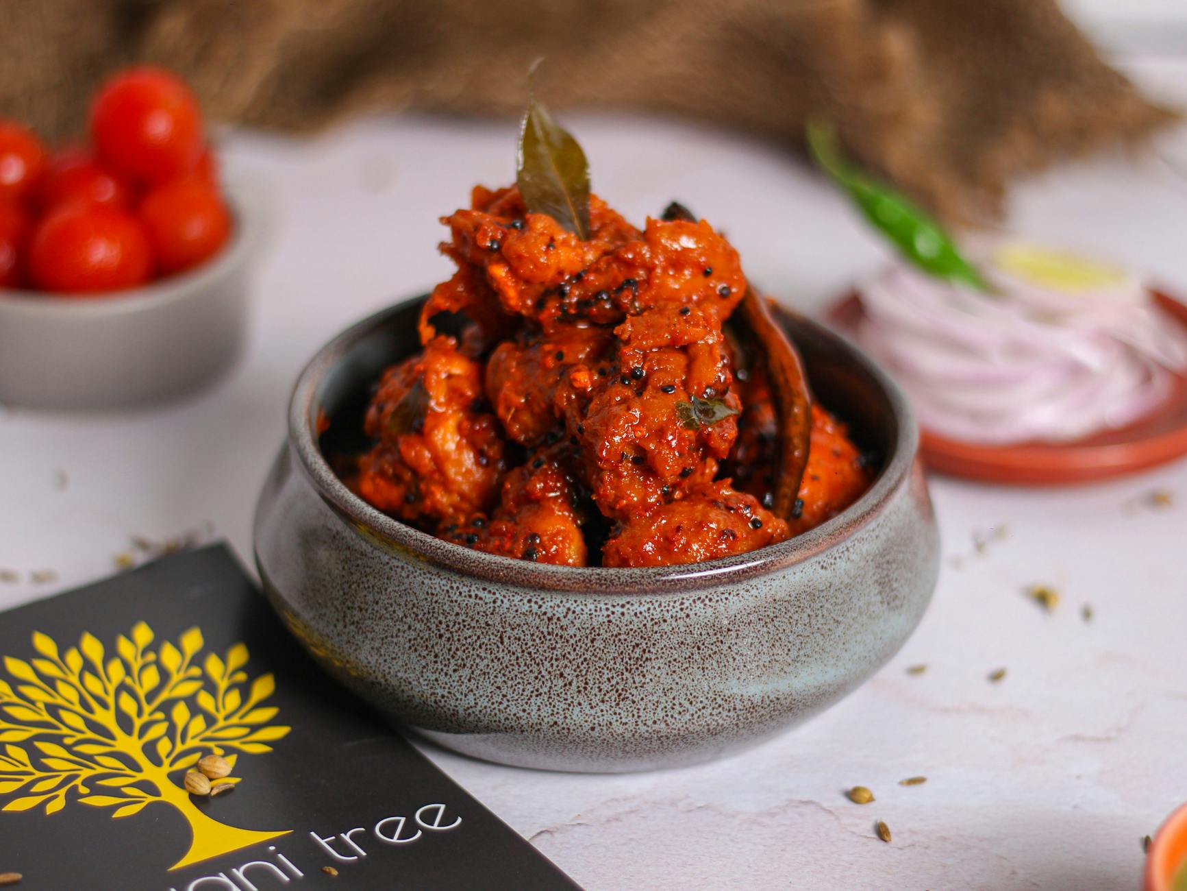 Close-up of a delicious Indian chicken curry dish served in a ceramic bowl with fresh spices.
