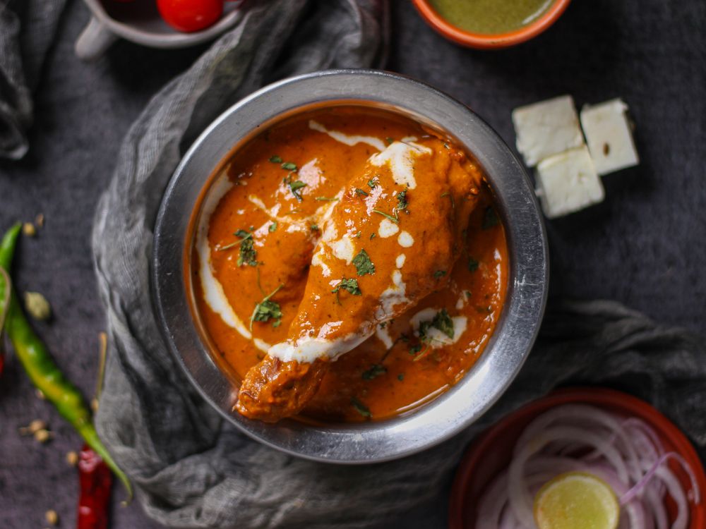 Butter chicken in a steel bowl finished with cream and herbs