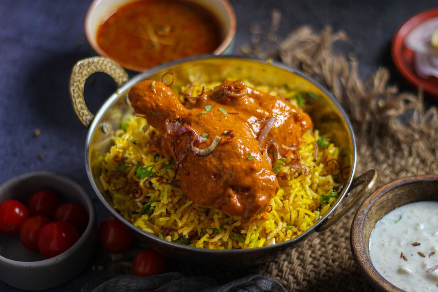 Delicious Indian chicken biryani served with accompanying curry and yogurt raita, capturing the essence of traditional cuisine.