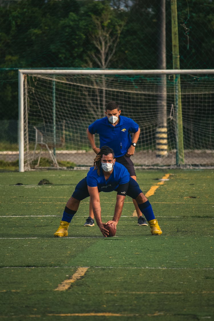 American Football Players In Facemasks Training On The Pitch 