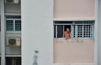 老人从城市高楼的窗户向外凝视，感到一阵孤独