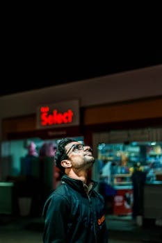 夜间，在巴基斯坦卡拉奇一家灯火通明的便利店外，一名戴眼镜的男子抬头仰望