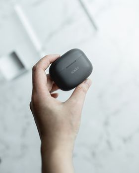 Close-up of a hand holding a sleek black wireless earbuds case, ideal for tech and lifestyle themes.