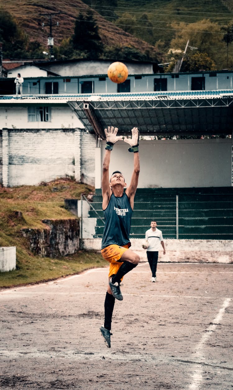 Man Jumping While Catching Soccer Ball