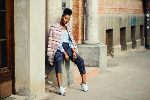 Woman Sitting on Gray Concrete Pillar