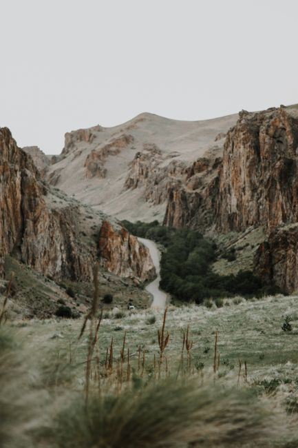 Serene canyon landscape with a winding path and rich greenery against rocky formations.
