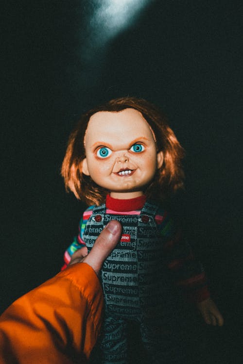 Person Holding Pop Culture Symbol Scary Horror Doll in Hand