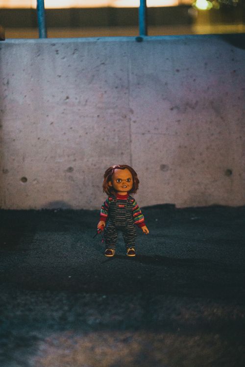 Free A chilling doll stands alone in an urban setting at night, creating a spooky ambiance. Stock Photo