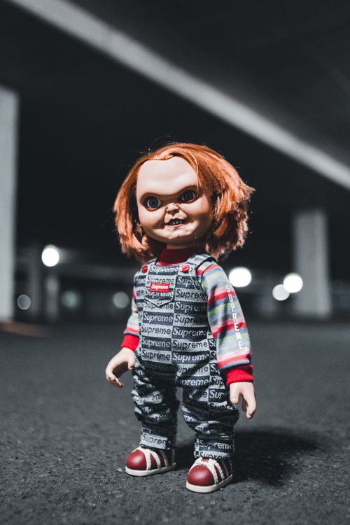 Free A chilling doll with a sinister expression stands in an empty parking garage. Stock Photo