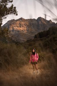 A walker crossing tall grass below a rock face, photo by Zakhar Vozhdaienko on Pexels