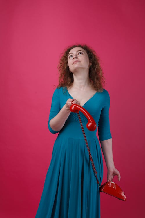 Woman in Blue Dress Holding a Telephone