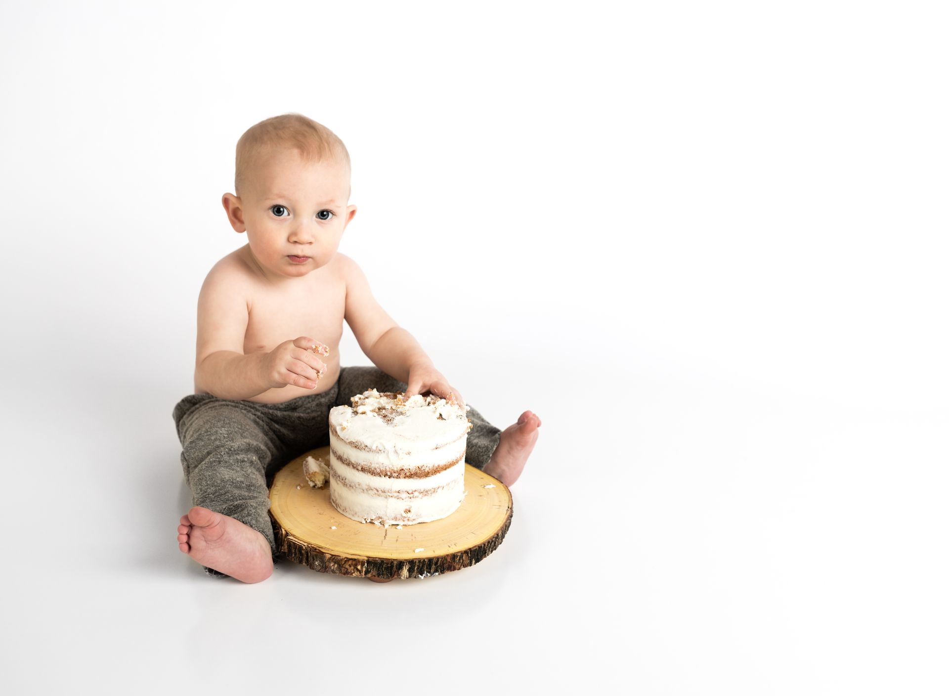 Cute baby enjoying a cake smash on white background, capturing innocence and joy.