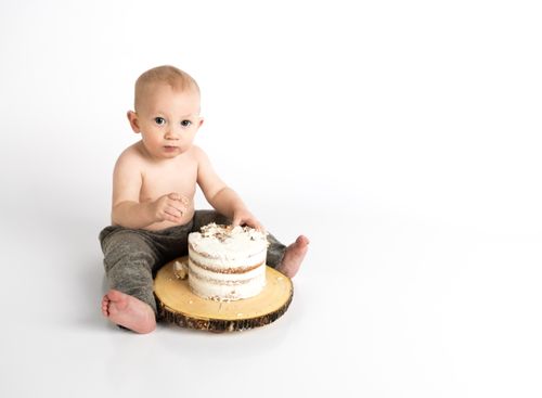 Free Cute baby enjoying a cake smash on white background, capturing innocence and joy. Stock Photo
