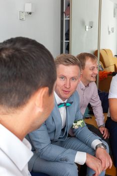 Groom with friends in a hotel room, sharing a joyful moment before the wedding ceremony.