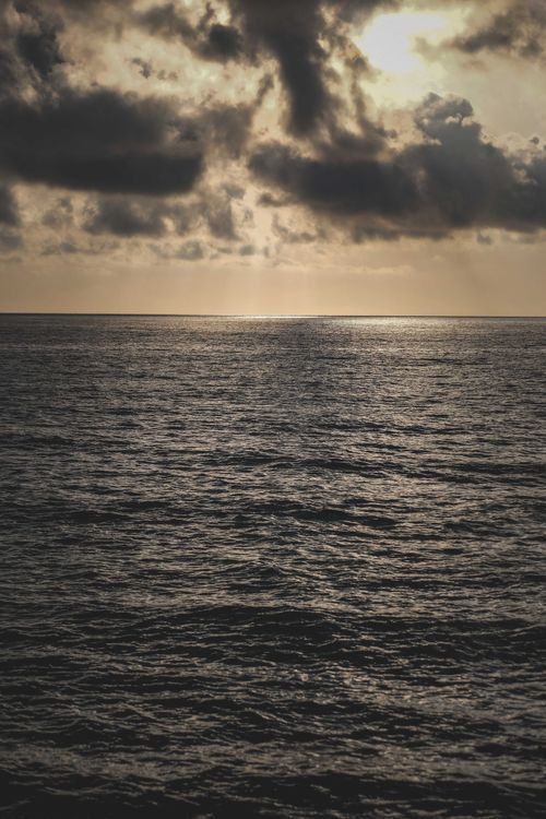 Free A moody seascape with dramatic clouds and rippling water at dusk, capturing a serene and atmospheric scene. Stock Photo