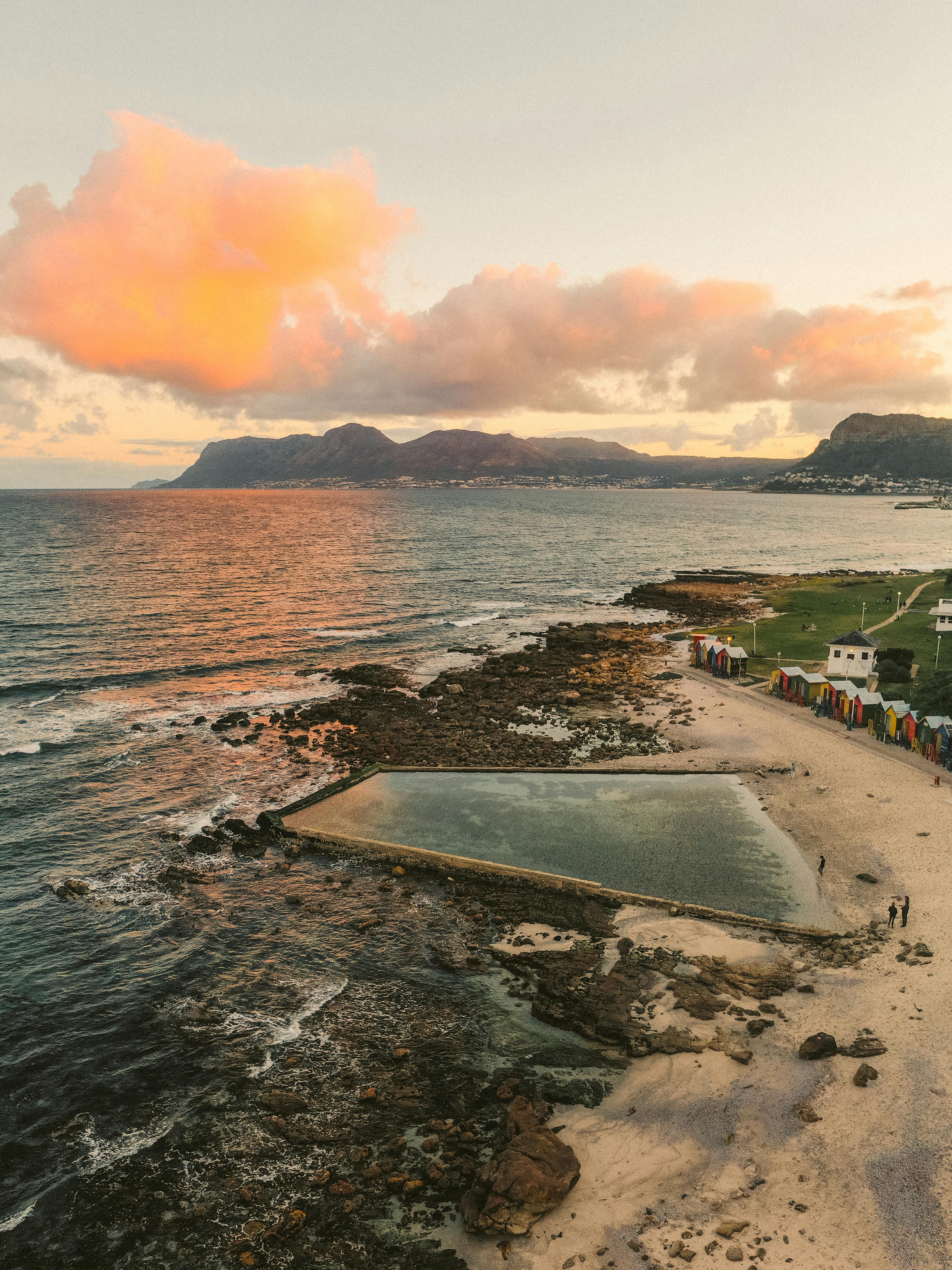 日落时令人惊叹的海岸线鸟瞰图，有游泳池和色彩缤纷的海滩小屋