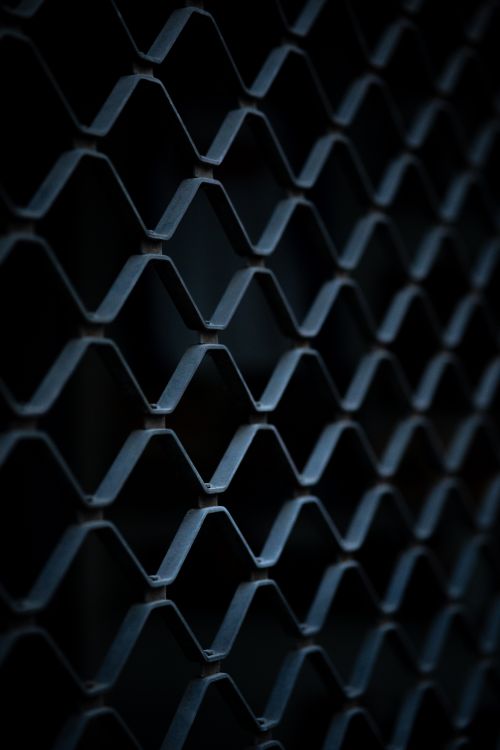 Free Dark close-up of a hexagonal metal fence showcasing intricate patterns and depth. Stock Photo