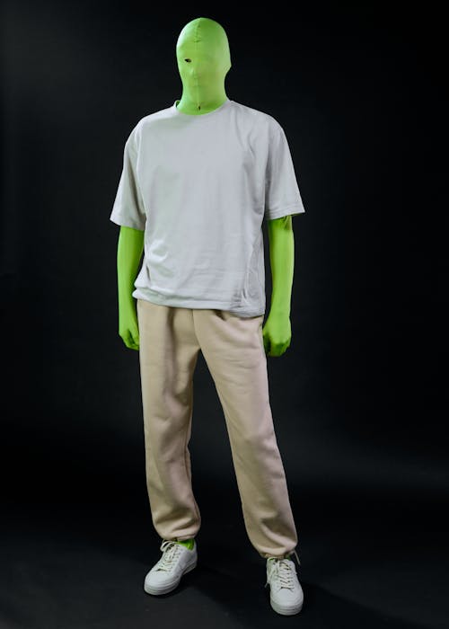 A Person in a Green Screen Suit Wearing a Gray Shirt and Beige Trousers