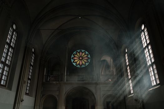 Sunrays streaming through stained glass windows inside a historical church, creating a serene ambiance.
