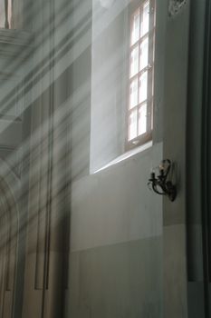 Gentle sunbeams stream through a window in a serene church, casting light on the walls.