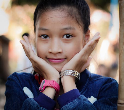 Girl Wearing Blue Top à Manches Longues Face Au Repos Sur Les Mains