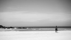 Grayscale Photography of a Man Walking on Beach