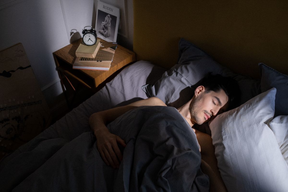 Person sleeping peacefully in bed with soft natural morning light entering the room
