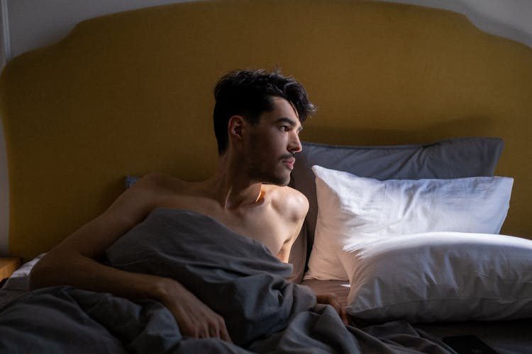 Topless Man Lying On Bed