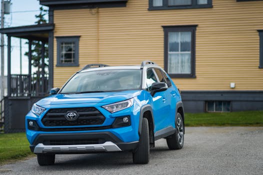 Blue Toyota RAV4 parked outside a house, showcasing modern SUV design.